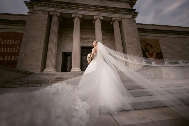 Bride standing posing with her wedding veil on the stairs outside the Cleveland Museum of art | by Kropp Photography - Cleveland Wedding Photographers